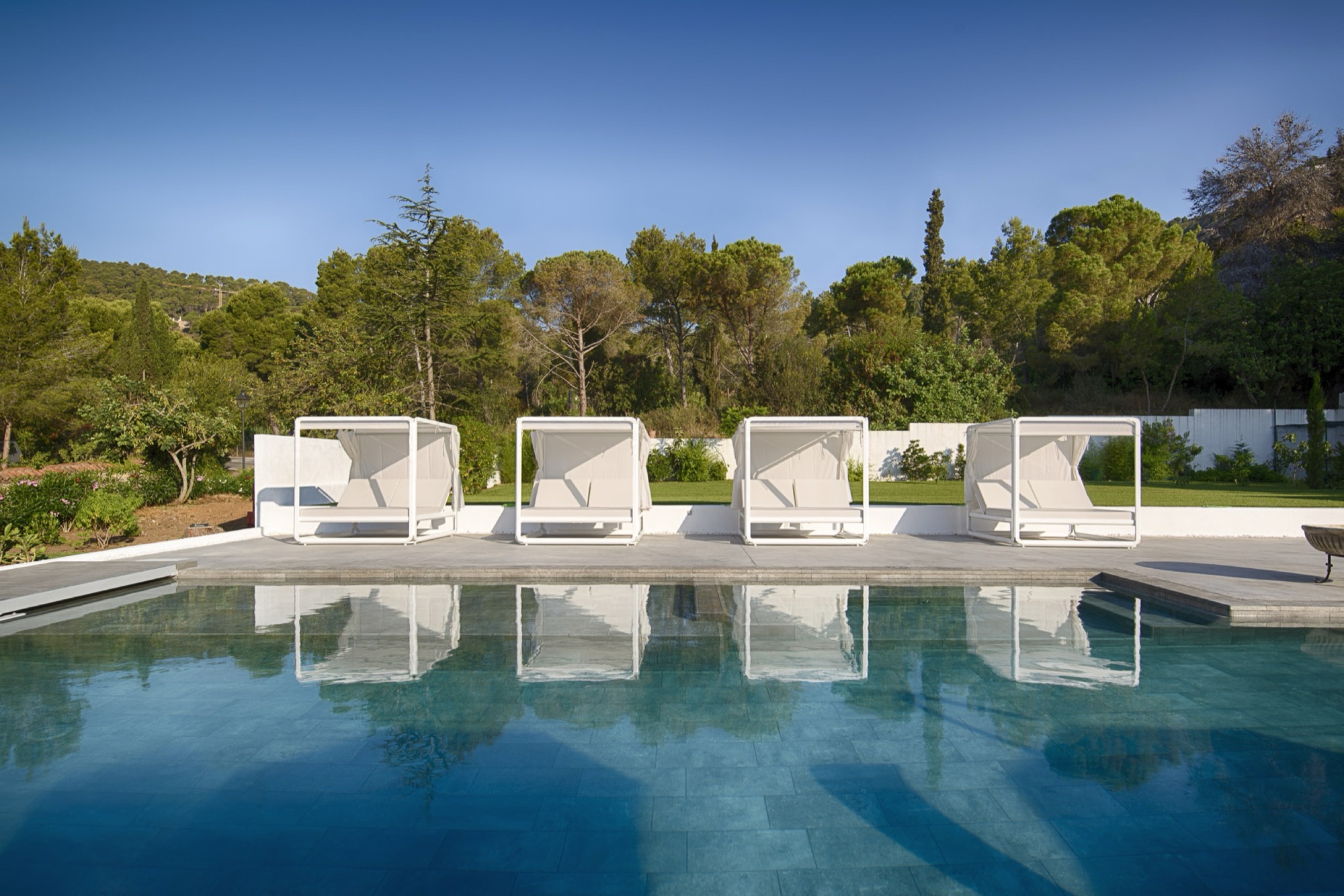 Ezpeleta white canopy cabana daybeds along a resort pool