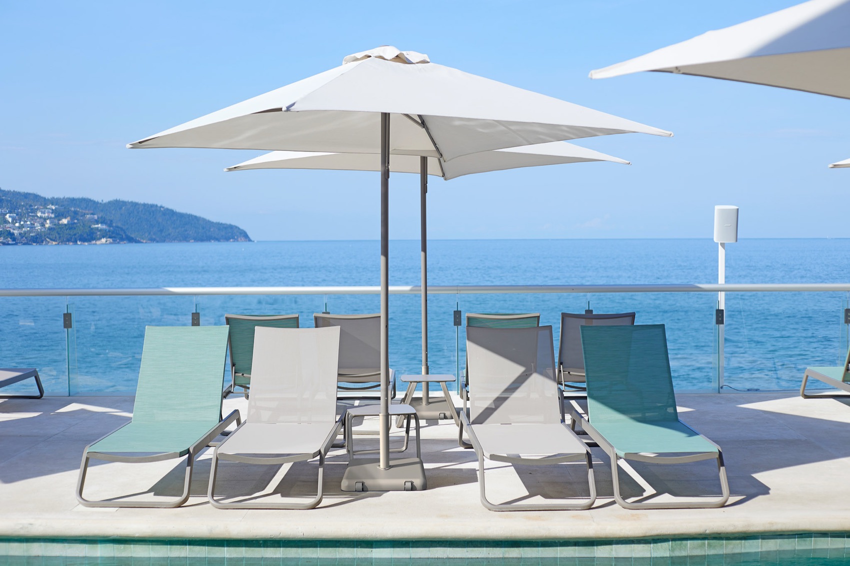 Ezpeleta sun loungers on a rooftop pool deck overlooking the sea
