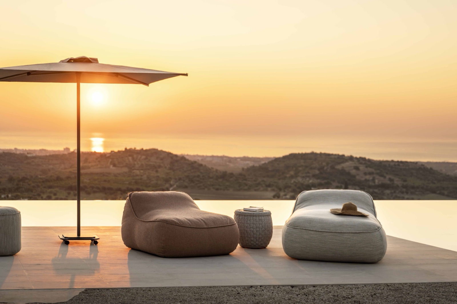 Jardinico lounge chairs and parasol at golden hour beside an infinity pool