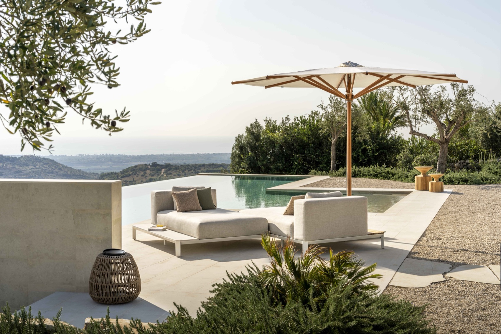 Jardinico wood-framed parasol shading a modular daybed by an infinity pool