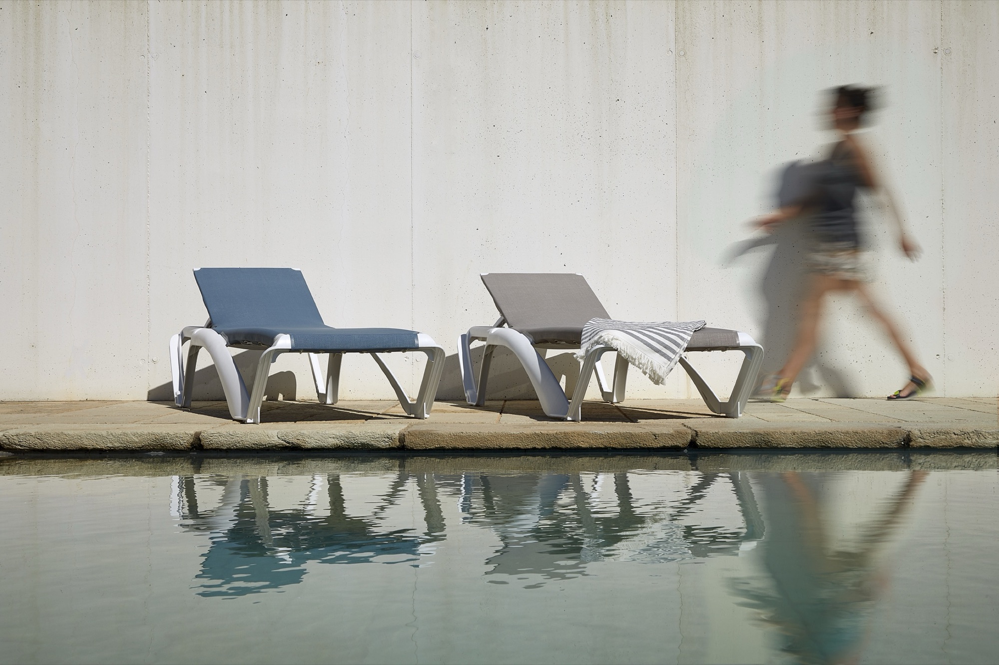 Resol Marina poolside sling sun loungers reflected in a pool