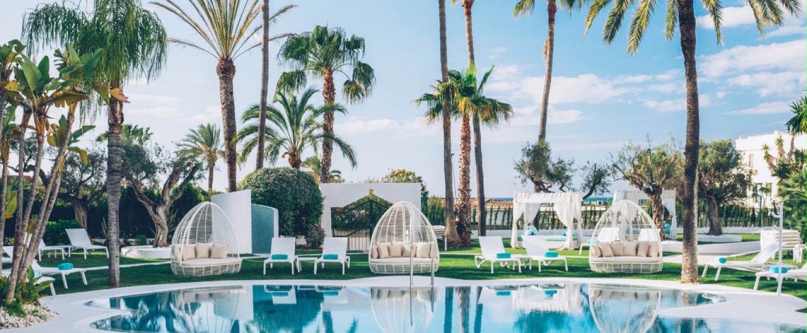 SKLD Studio white woven egg pod daybeds and cabanas by a pool