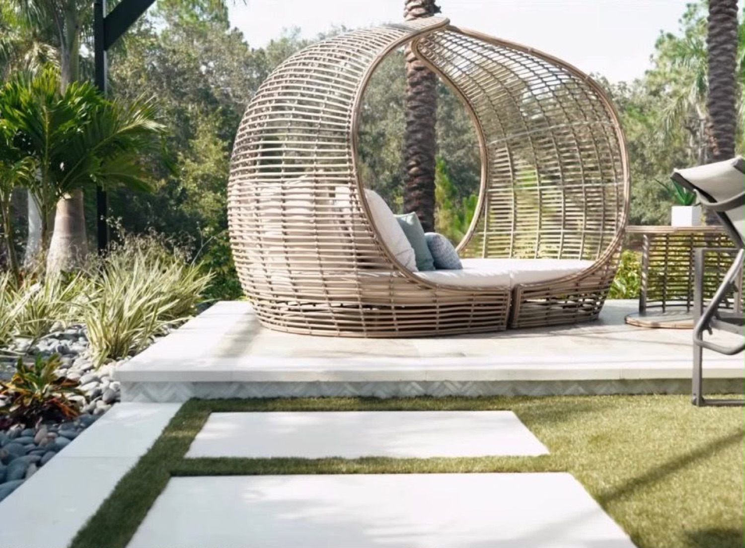 SKLD Studio Nest woven rattan pod daybed on a garden pool deck